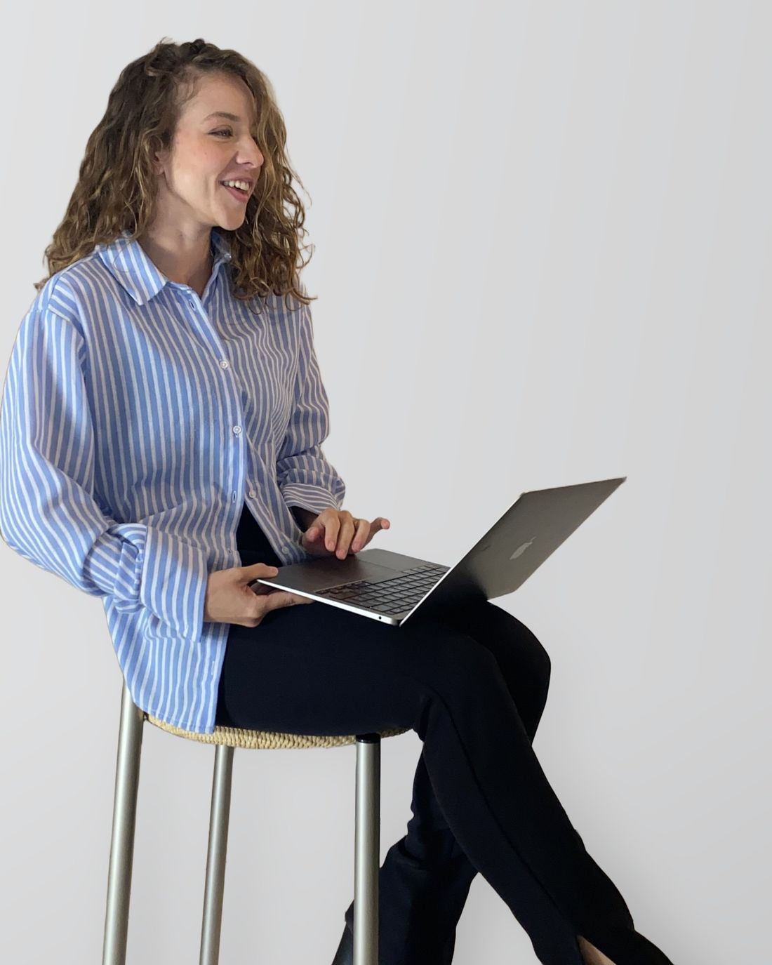 Bethania, founder of Lucerna Web Studio, laughing on a stool